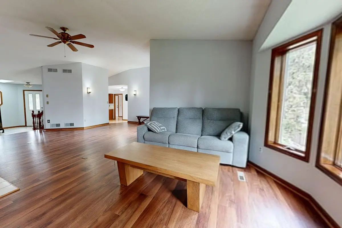 Open living room with new hardwood flooring, a gray sofa and large windows