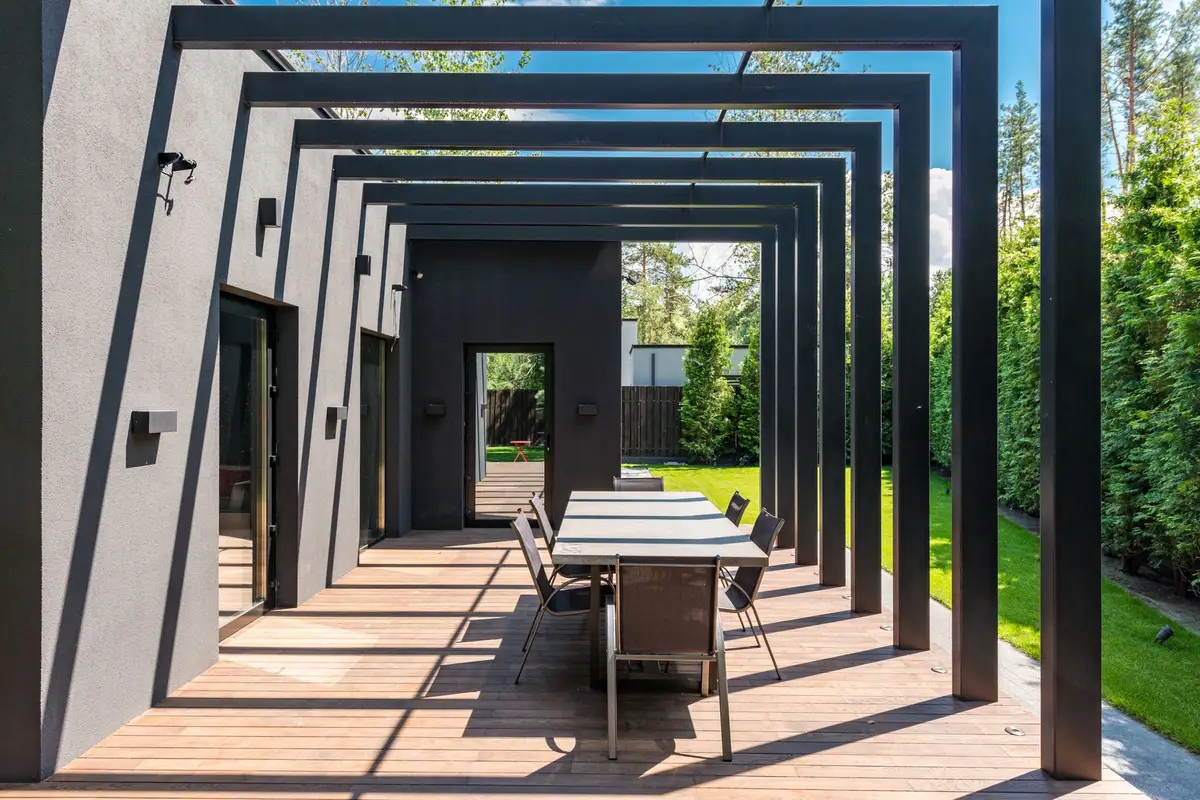 Contemporary patio with a dark pergola frame over an outdoor dining table